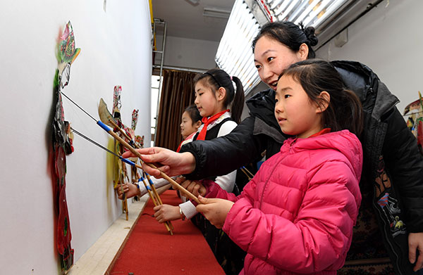 Students practice shadow puppetry under the guidance of their teacher at Zhongshan Experimental School in Luanxian, Hebei province.(Mu Yu / Xinhua)