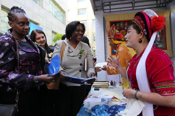 Fabric artist Duan Yinkai (right), master of traditional batik techniques in Yunnan province, speaks to foreign guests who attended a meeting in Beijing on China's poverty alleviation efforts on Thursday.  (Photo by Wang Zhuangfei / China Daily)