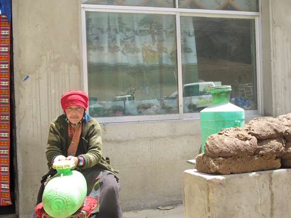 A Tibetan woman makes yogurt in front of her new home in Nyantok village of Menba township of Nyalam county, Tibet autonomous region. (Photo by Palden Nyima/chinadaily.com.cn)