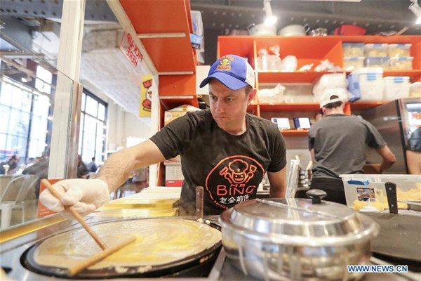 Brian Goldberg makes Jianbing at the kiosk of Mr. Bing in UrbanSpace food court in New York, the United States, April 17, 2017. (Photo/Xinhua)