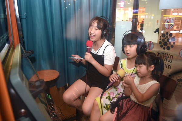 Customers sing at the mini karaoke booths in the basement of the Tianfu Square in Chengdu, capital of Sichuan province. There are four such mini booths here. It will cost 80 yuan ($11.6) for an hour of singing. (Photo by Hao Fei/For China Daily)