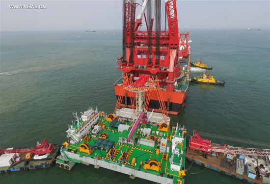A gigantic crane, which was transformed from a tanker, hoists a 6,000-ton key structure of the world's longest cross-sea bridge linking Hong Kong, Zhuhai and Macao, May 2, 2017. (Xinhua/Liu Dawei)
