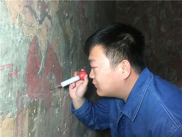 Veteran fresco restorer Li Yunhe's grandson Li Xiaoyang works on fresco restoration.