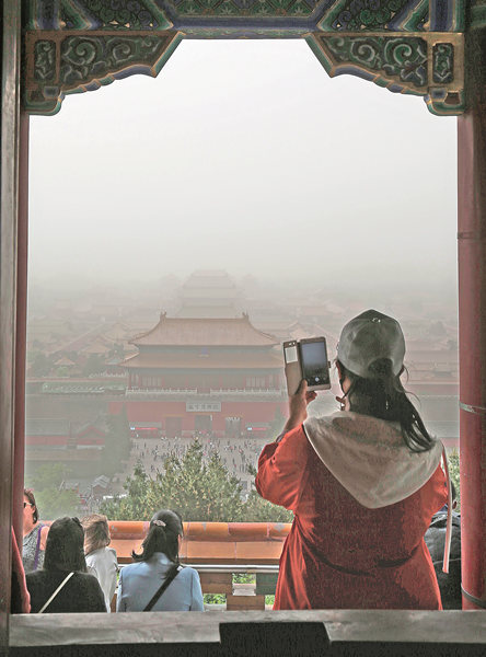 A visitor takes a photo of the Forbidden City through the haze of a sandstorm.