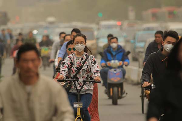 Cyclists in Tianjin wear masks on Friday, as dust hits the city. (Photo/Xinhua)
