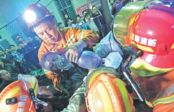 Rescuers put an oxygen mask on a miner who was extracted from a coal mine in Youxian county, Hunan province, early on Monday. A poisonous gas leak on Sunday morning killed 18 people in the mine. Another 37 were sent to the hospital. Li Ga / Xinhua