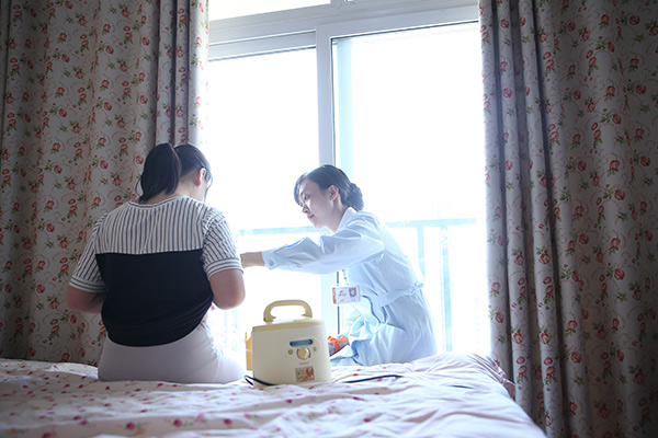 A nurse helps Wei Na to collect brest milk at Wei's home. (Photo provided to China Daily)