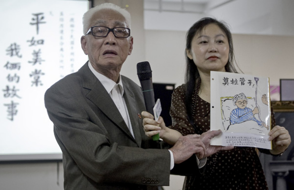 Rao Pingru (left) displays one of his drawings during a book promotion for Our Story, an artistic memoir for his late wife. (Photo by SUN ZHAN/CHINA DAILY)
