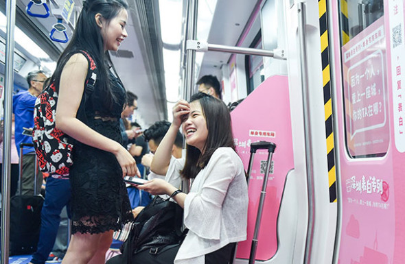 Passengers enjoy a light moment in a compartment prepared especially for singles on Line 1 of the Shenzhen Subway in Guangdong province on May 8.(Mao Siqian/Xinhua)