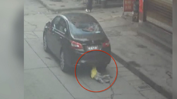 A car runs over a little girl crossing a road in Tianzhu county of southwest China's Guizhou Province on Friday. (Photo/Screenshot from CGTN)