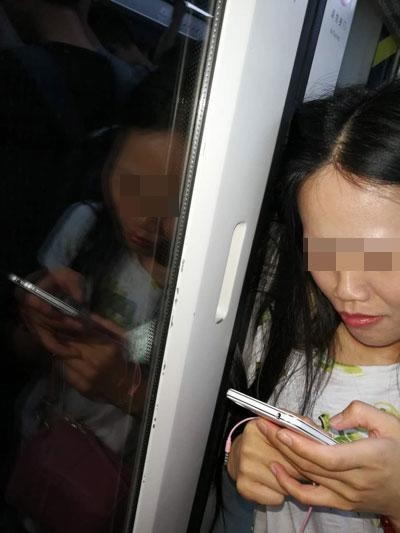 A woman plays with her mobile phone as she waits for doors to open and free her locks. (Photo/ycwb.com)