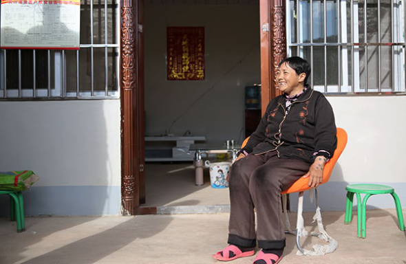 Jinhuo Buwei sits outside her new home in Binchuan, Yunnan province.(Hou Liqiang/China Daily)