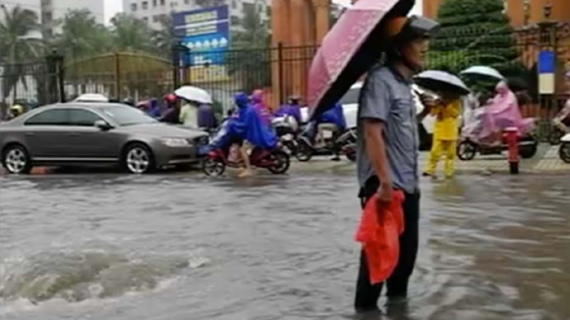 A man stands beside a whirlpool after a  manhole cover is washed away on Xiuzhong road in Haikou, Hainan Province. (Photo/CGTN)