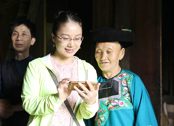 A tourist takes a picture recently with 68-year-old Shi Basan. President Xi Jinping visited Shi's family in 2013 and introduced the concept of targeted poverty alleviation.(Hao Qunying/For China Daily)