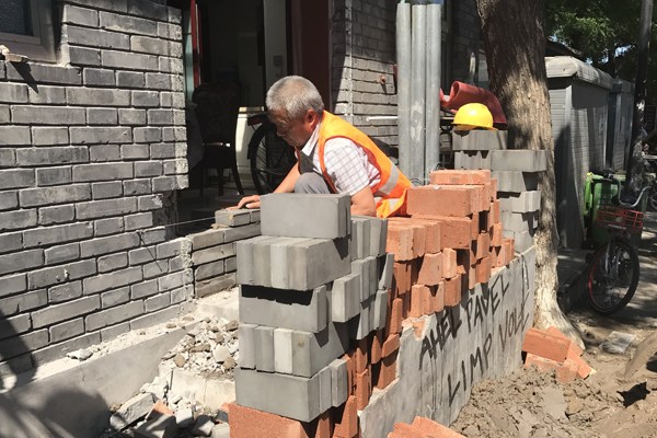 A builder finishes a brick wall in Fangjia Hutong in Beijing on Tuesday. Xin Wen / For China Daily