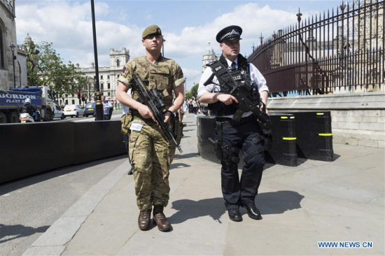 An armed soldier and an armed police officer patrol outside the Houses of Parliament in London, Britain, on May 24, 2017. British Prime Minister Theresa May announced Tuesday night that the country's terror threat level has been raised from severe to critical, its highest level. (Xinhua/Ray Tang)