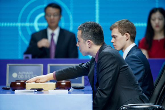 Gu Li plays with AlphaGo's hand watching during the Paired Go team match. (Photo/CGTN)