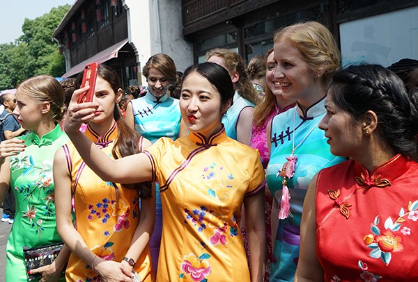 Women from different countries wear qipao, the traditional Chinese dress, and pose for a selfie during the Hangzhou Global Qipao Festival in Zhejiang province on Friday. DONG XUMING/CHINA DAILY