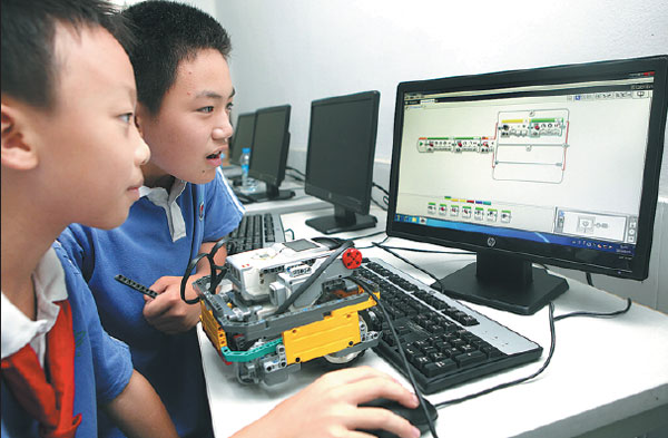 Two students create a program for a Lego robot with a computer, at a primary school in Shenzhen. Zhao Yanxiong / For China Daily