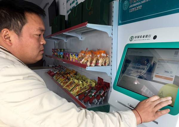 Xiao Chuanguo, a resident of Fazi village in Chongqing's Wulong district, uses Agricultural Bank of China's integrated financial services on a bank terminal.(Photo by Tan Yingzi/China Daily)