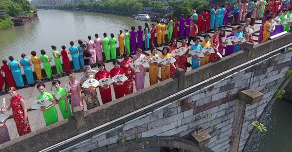 Women wearing qipao, the body-hugging traditional Chinese dress, pose for photos on a bridge in Hangzhou, capital city of East China's Zhejiang province, on May 26. (Photo/provided to chinadaily.com.cn)