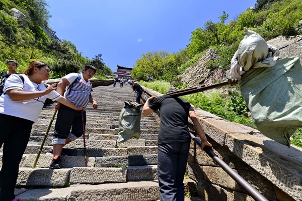 A porter carries a heavy load up Taishan Mountain in Shandong province. The number of porters has fallen sharply to fewer than 40 because of the growth in modern transportation.Photos By Ju Chuanjiang / China Daily