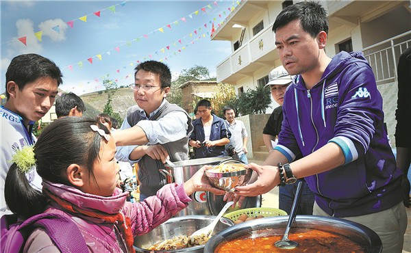 Deng Fei serves free meals to children in Yi-Hui-Miao autonomous county, Guizhou. (Photo by Zhao Junxia for China Daily)