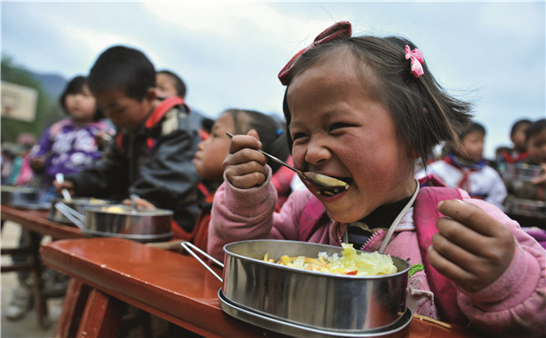 Children are enjoying their free lunch at Shaba Primary School of Qianxi County, Guizhou Province in 2011. (Photo by Zhao Junxia for China Daily)