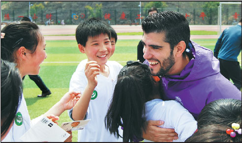 Victor De Arce, of the Real Madrid Foundation, hugs a student after a soccer training session.