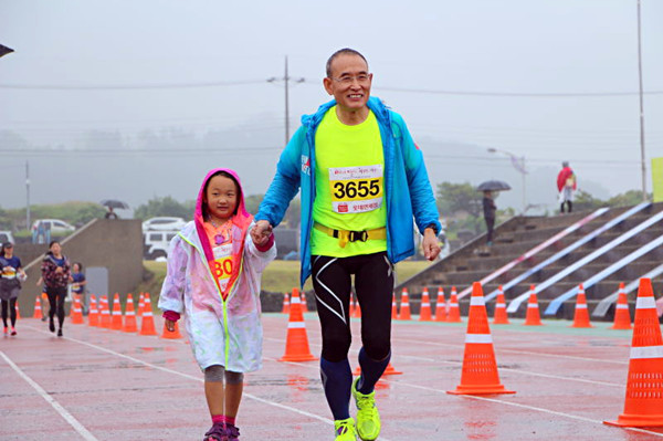 Tian Tongsheng and his daughter Tian Songran approaching the Jeju Marathon 2016 finish line, hand in hand. Photo provided to Chinadaily.com.cn