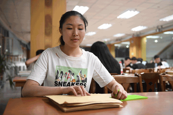 Yu Ya'nan, a student majoring in piano performance at Changchun University's Special Education School, studies English at a library on Friday. Yu was one of the first five blind students to take the College English Test. ZHANG NAN/XINHUA