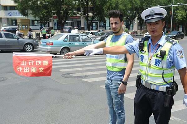 A Palestinian assists a policeman directing traffic at an intersection in Jinan, Shandong province, June 18, 2017. (Photo by Xu Zhenggang/provided to chinadaily.com.cn)