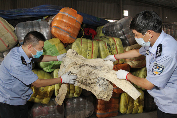 Members of the anti-smuggling unit of the Xiamen Customs, Fujian province, uncover illegally imported waste material. LEI GUOHUA/CHINA DAILY