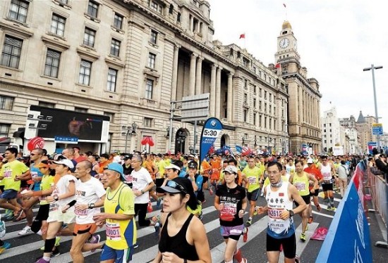 Shanghai International Marathon participants run from the start on the Bund yesterday.(Photo/Xinhua)