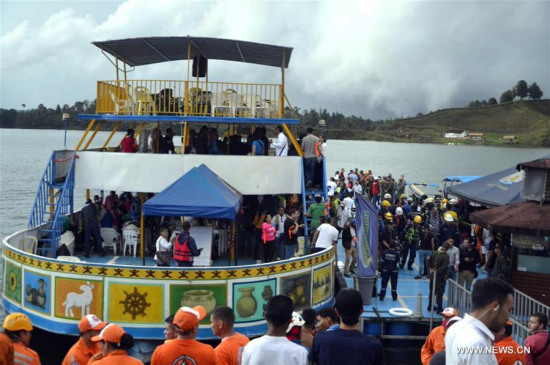 Image provided by Antioquia Police shows rescuers and police officers boarding a boat towards the site where a tour boat capsized in Guatape, Antioquia Department, Colombia, on June 25, 2017. (Photo/Xinhua)