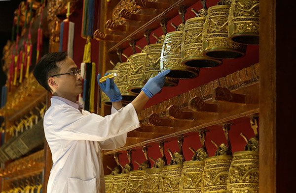 An expert checks the Set of Bronze Bells with Double-Dragon Knob and Dragon-Cloud Design collection of the Palace Museum, dating from the 52nd year of the Kangxi reign (1713), as crates are opened at the Hong Kong Museum of History.Roy Liu / China Daily