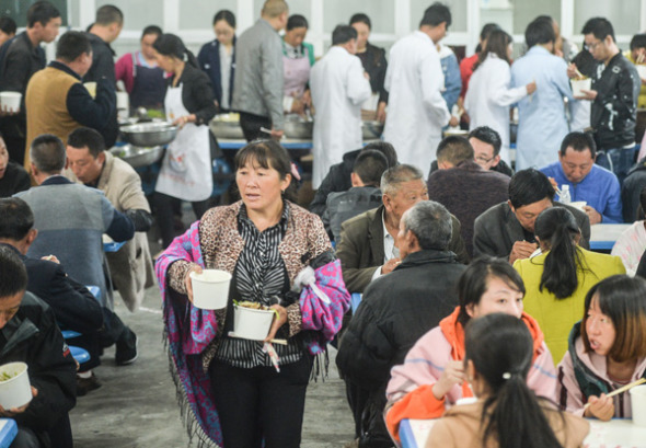 Villagers affected by the landslide wait for supper at a center for displaced residents on Tuesday night. The center, located in an elementary school, provides accommodations and counseling services. (Photo by Hao Fei/China Daily)