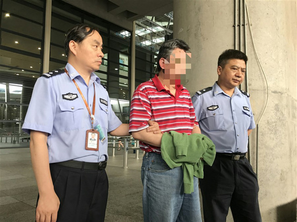 The suspect surnamed Du (center) is escorted by police after arriving in Shanghai from Canada on June 20.  (Photo: Shanghai Daily/Ti Gong)