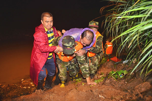 Rescuers help villagers to safety on Tuesday night in Zhiping village in Shaoyang city, Hunan province, where roads to the village were cut off by landslides triggered by heavy rainfall.Tang Jun / For China Daily
