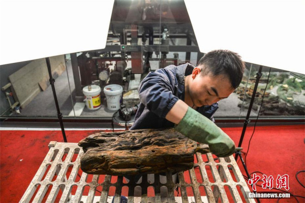 An archaeologist cleans a section of the Huaguangjiao No.1 at the Hainan Museum in Haikou, capital of Hainan province, June 1, 2017. (Photo/Chinanews.com)