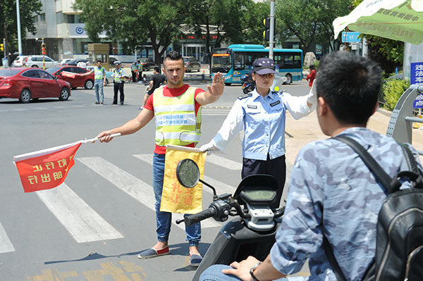 A Palestinian assists a policewoman directing traffic at an intersection in Jinan, Shandong province, June 18, 2017. (Photo by Xu Zhenggang/provided to chinadaily.com.cn)
