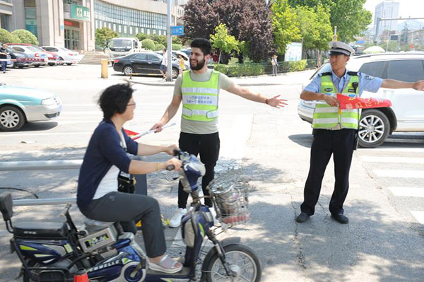 A Palestinian assists a policeman directing traffic at an intersection in Jinan, Shandong province, June 18, 2017. (Photo by Xu Zhenggang/provided to chinadaily.com.cn)
