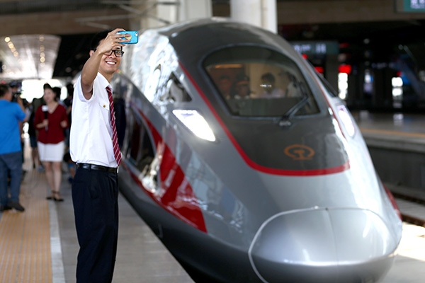 A man takes a photo with a Fuxing bullet train before its departure for Shanghai from Beijing. (Photo/Xinhua)