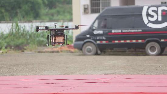 An SF Express worker picks up a package delivered by a small drone. (Photo/guancha.cn)