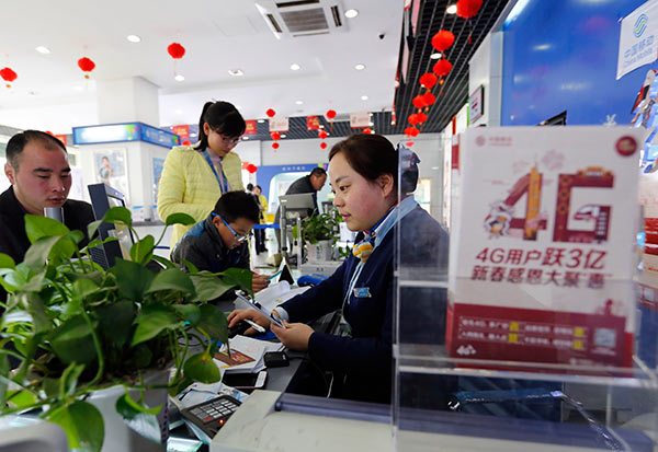 A China Mobile staff member in Ganyu, Jiangsu province, helps a client with 4G service. (Photo by Si Wei/For China Daily)