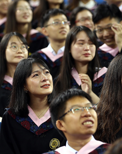 Graduates of Peking University weep while watching videos reviewing their college days during a graduation ceremony in Beijing on Tuesday. (Photo by Zou Hong/China Daily)