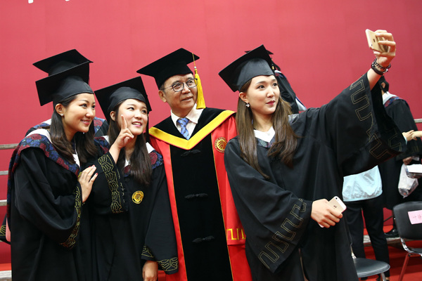 Graduates of Peking University take a selfie with Lin Jianhua, president of the university, after their graduation ceremony in Beijing on Tuesday. (Photo by Zou Hong/China Daily)