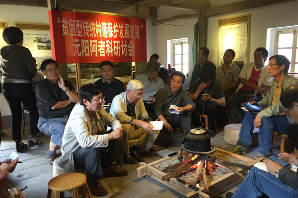 Zhu Liangwen (fifth from left) discusses the Azheke renovation project at the village in Yuanyang county, Yunnan province, with local officials and village leaders. FU ZHENGHUI/CHINA DAILY