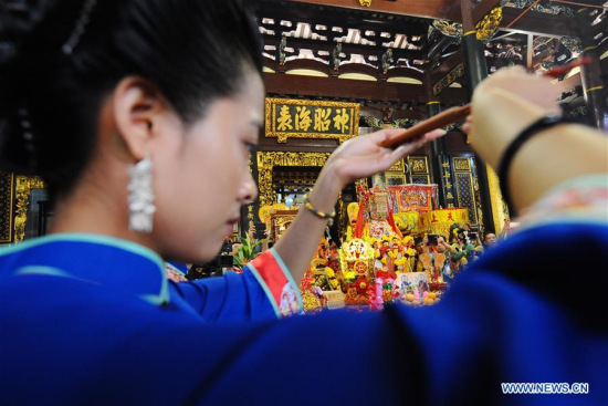 A ceremonial attendant holds up incense sticks during the prayer ceremony for the deity Mazu from Meizhou place at Singapore's Thian Hock Keng temple on July 6, 2017. (Xinhua/Then Chih Wey)