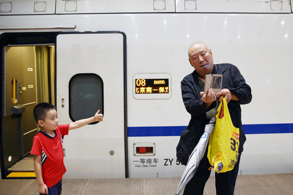 A passenger takes a photo of his grandson at Beijing South Railway Station on Thursday before they board a bullet train heading to Baigou in Hebei province. ZOU HONG/CHINA DAILY